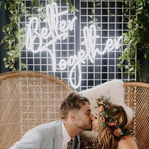 bride and groom kissing in front of Better Together Neon Sign