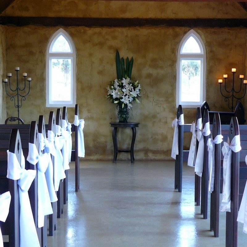 church pews with white wedding ribbons
