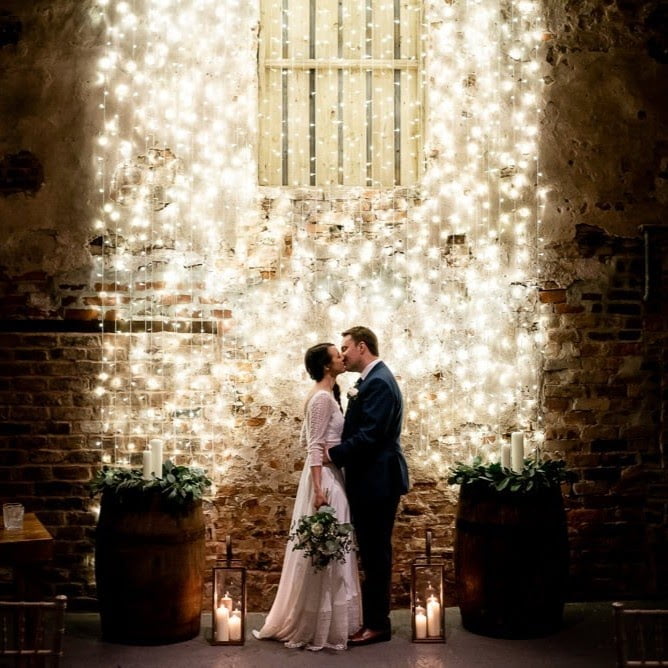 bride and groom in front of brightly lit wall