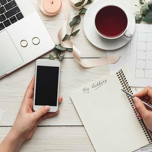 phone, notepad and coffee on table planning a wedding